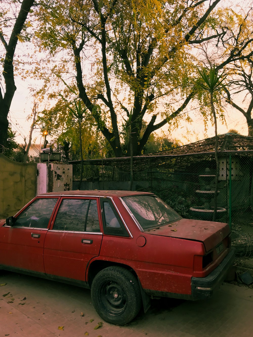 a red car parked in front of a fence