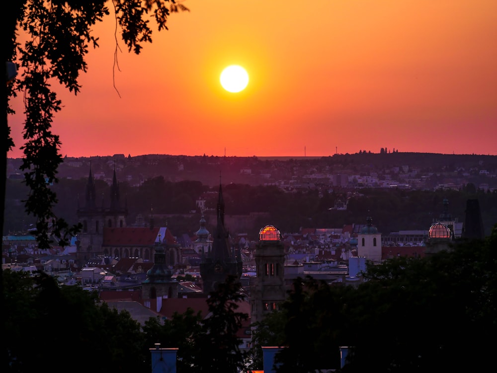 the sun is setting over a city with tall buildings