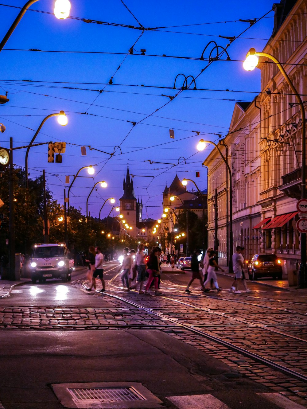 a city street at night with people crossing the street