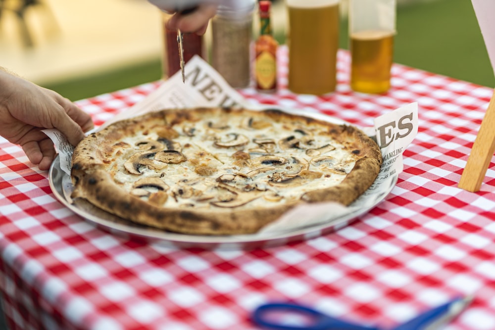 a pizza on a plate on a table with a red and white checkered table