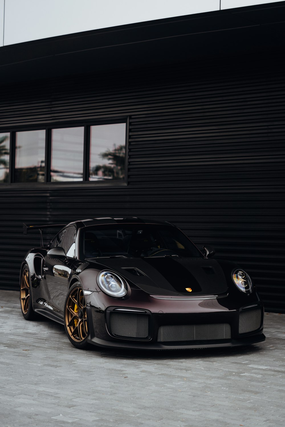 a grey and black sports car parked in front of a garage