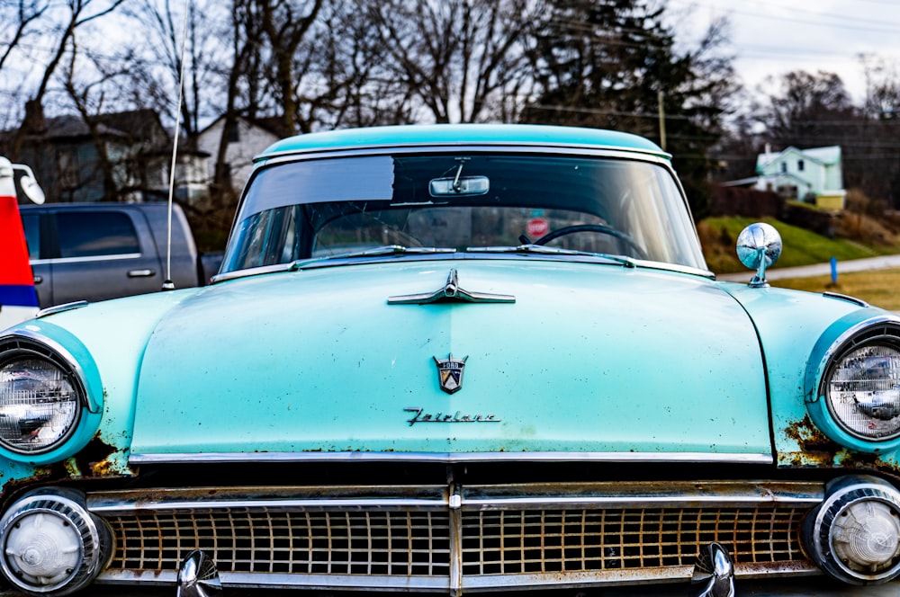 an old blue car parked in a parking lot