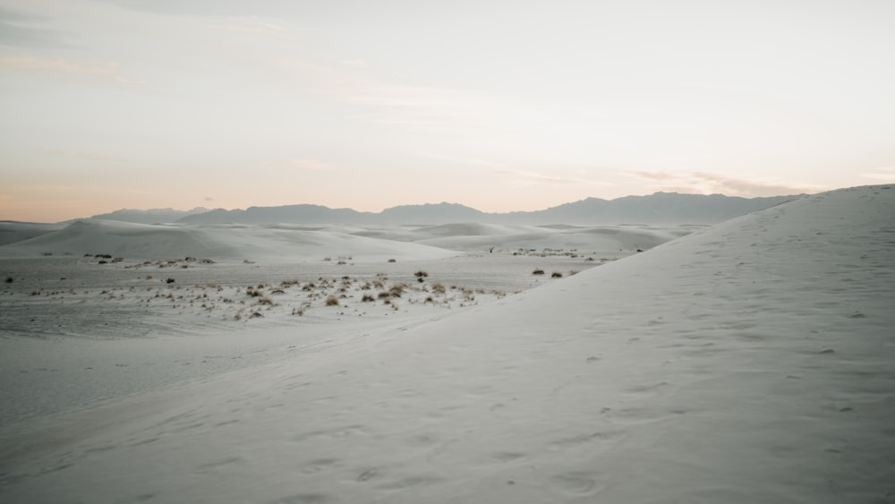 a snow covered field with mountains in the background