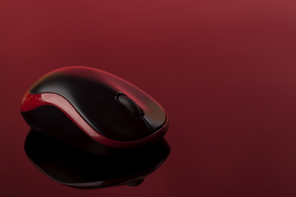 um mouse de computador vermelho e preto em uma superfície vermelha