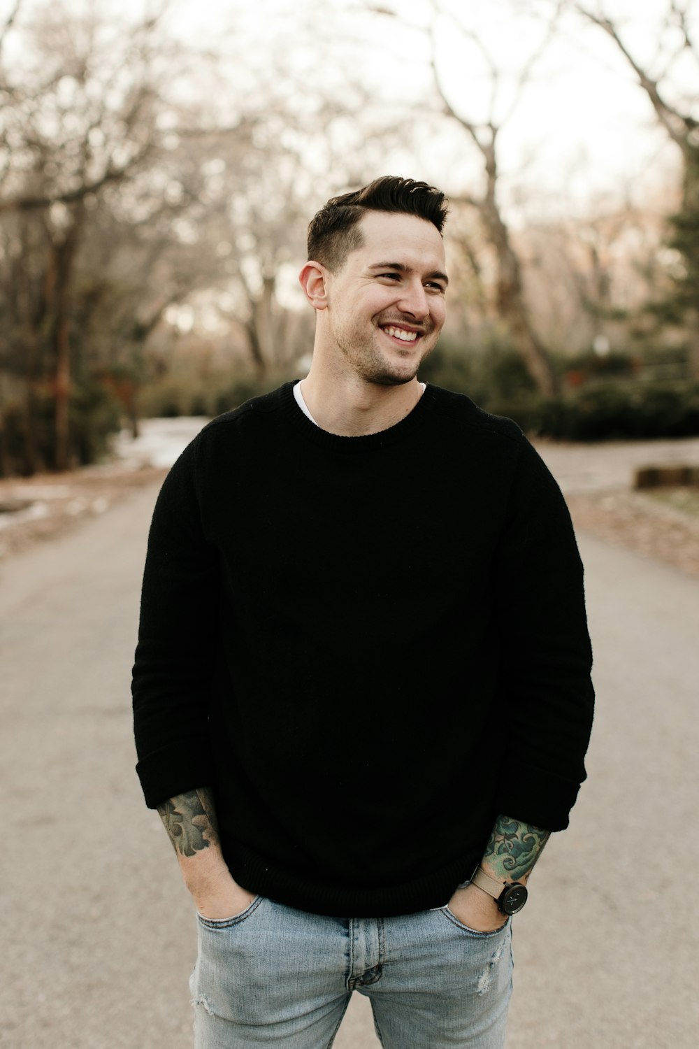 a man with tattoos standing in the middle of a road