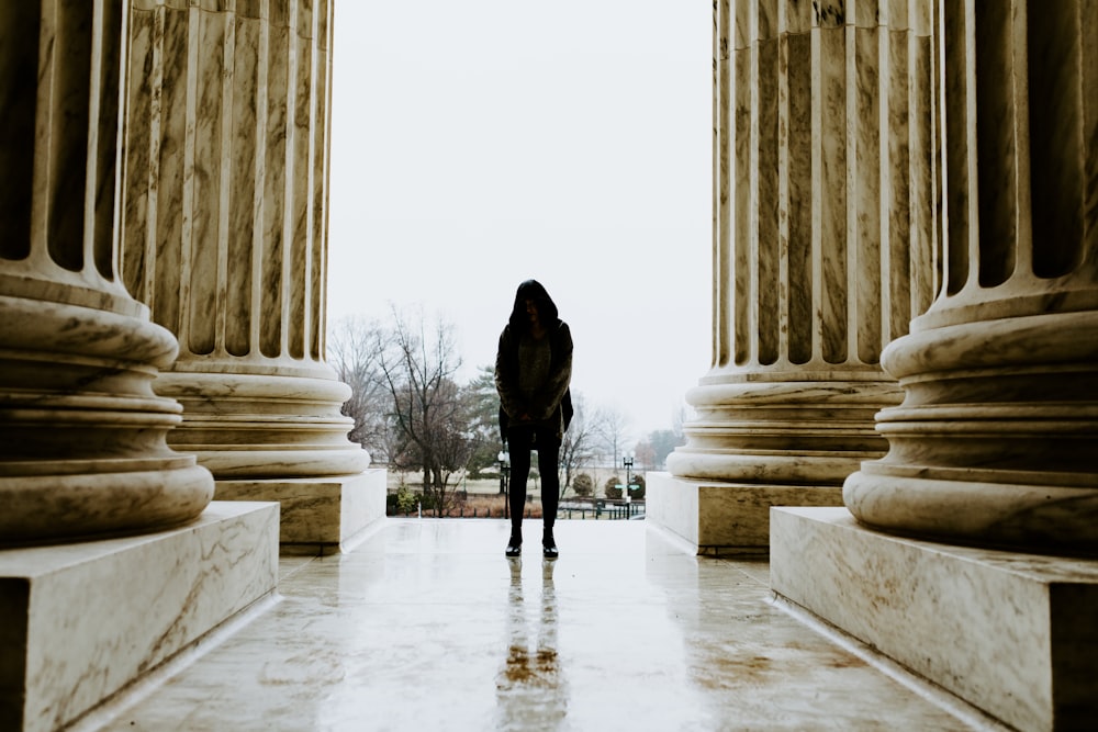 a person standing in front of columns in a building