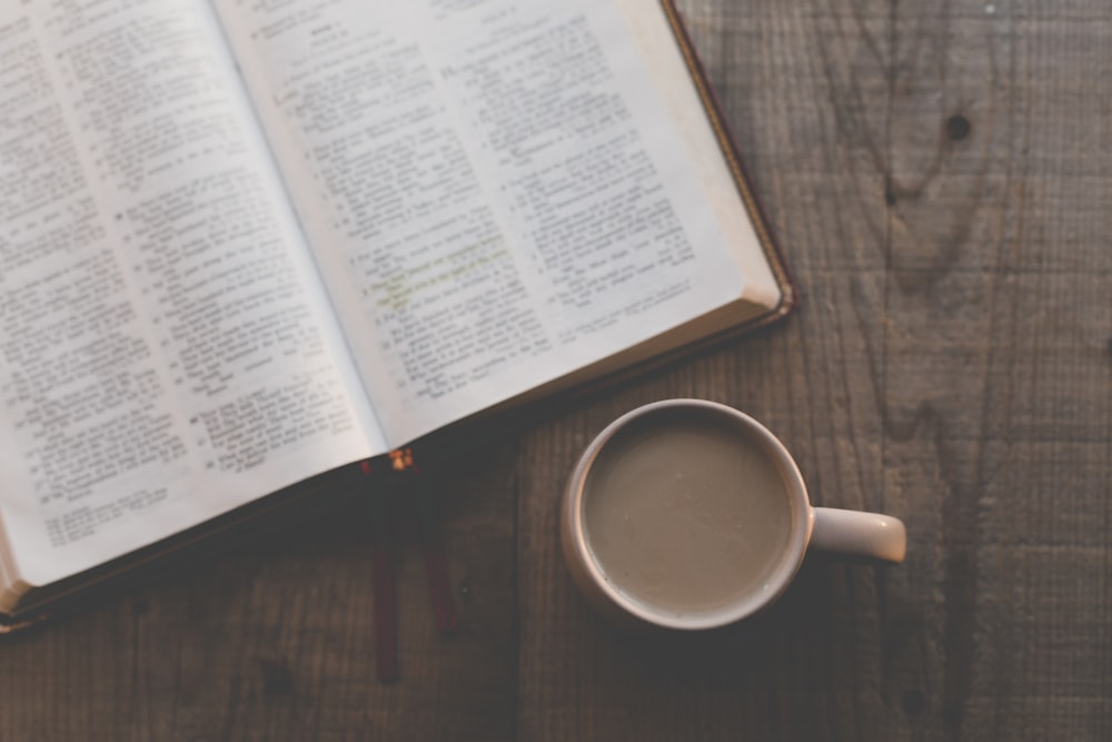 an open book and a cup of coffee on a table