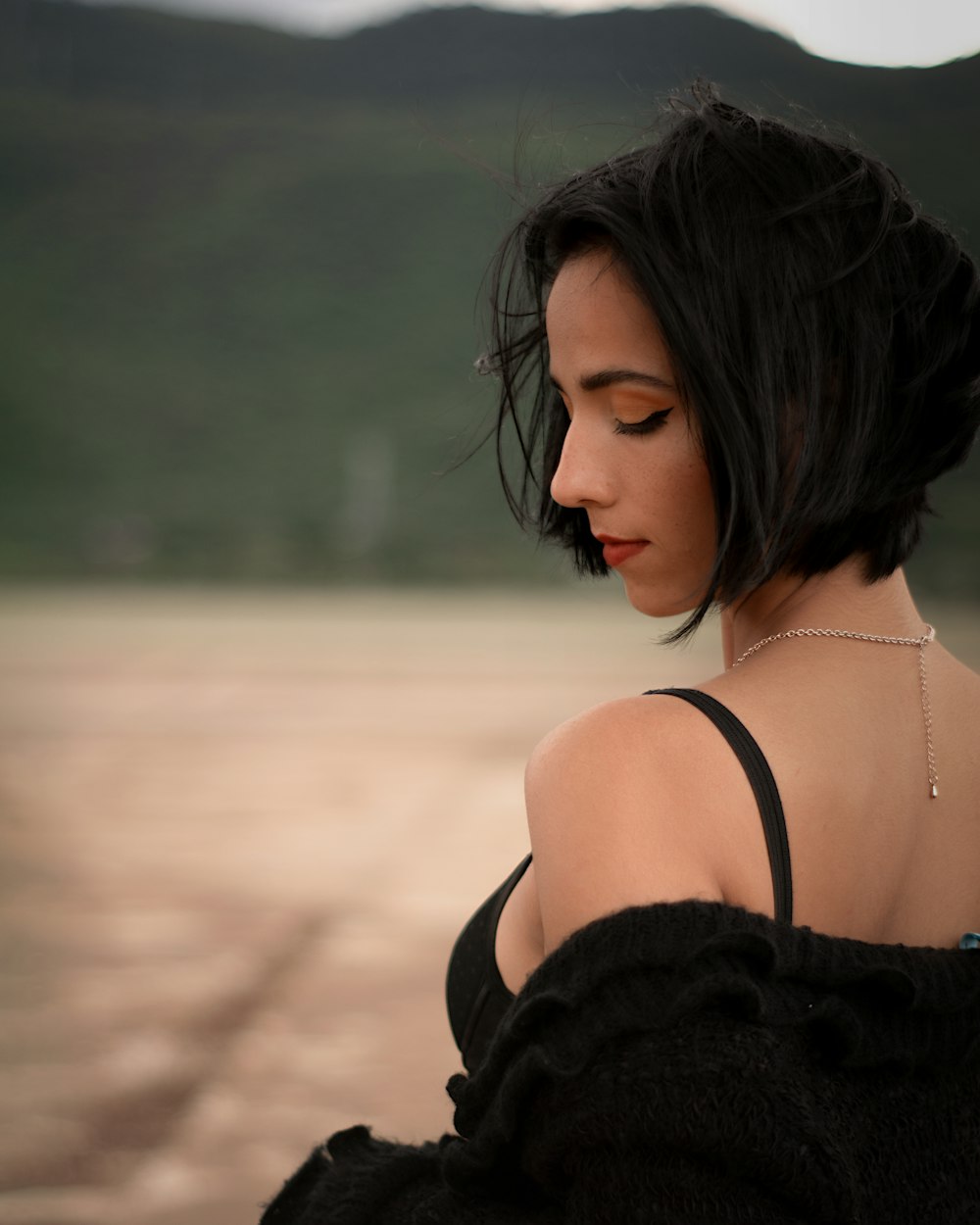 a woman in a black dress looking down at her cell phone