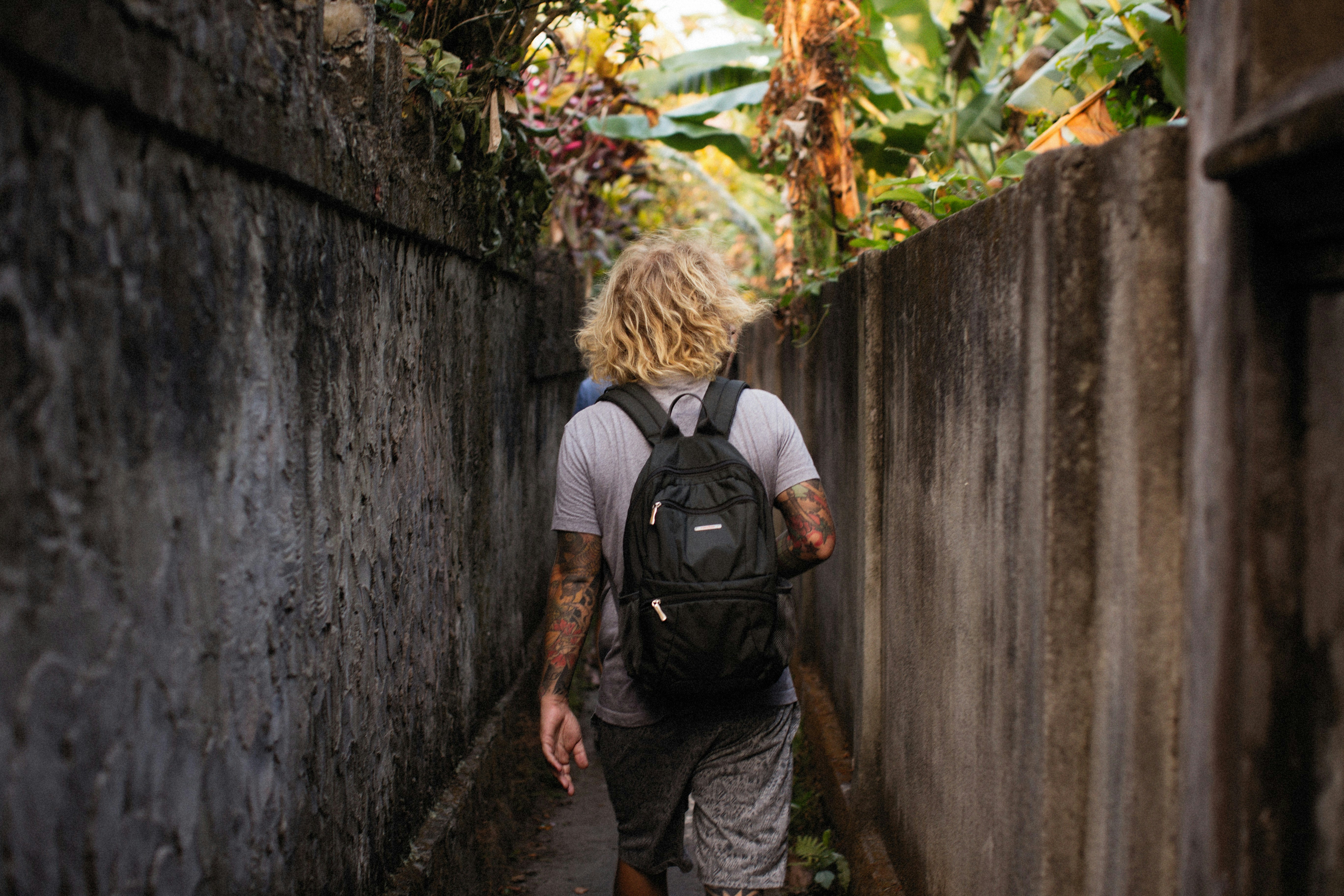 a man with a backpack walking down a narrow street