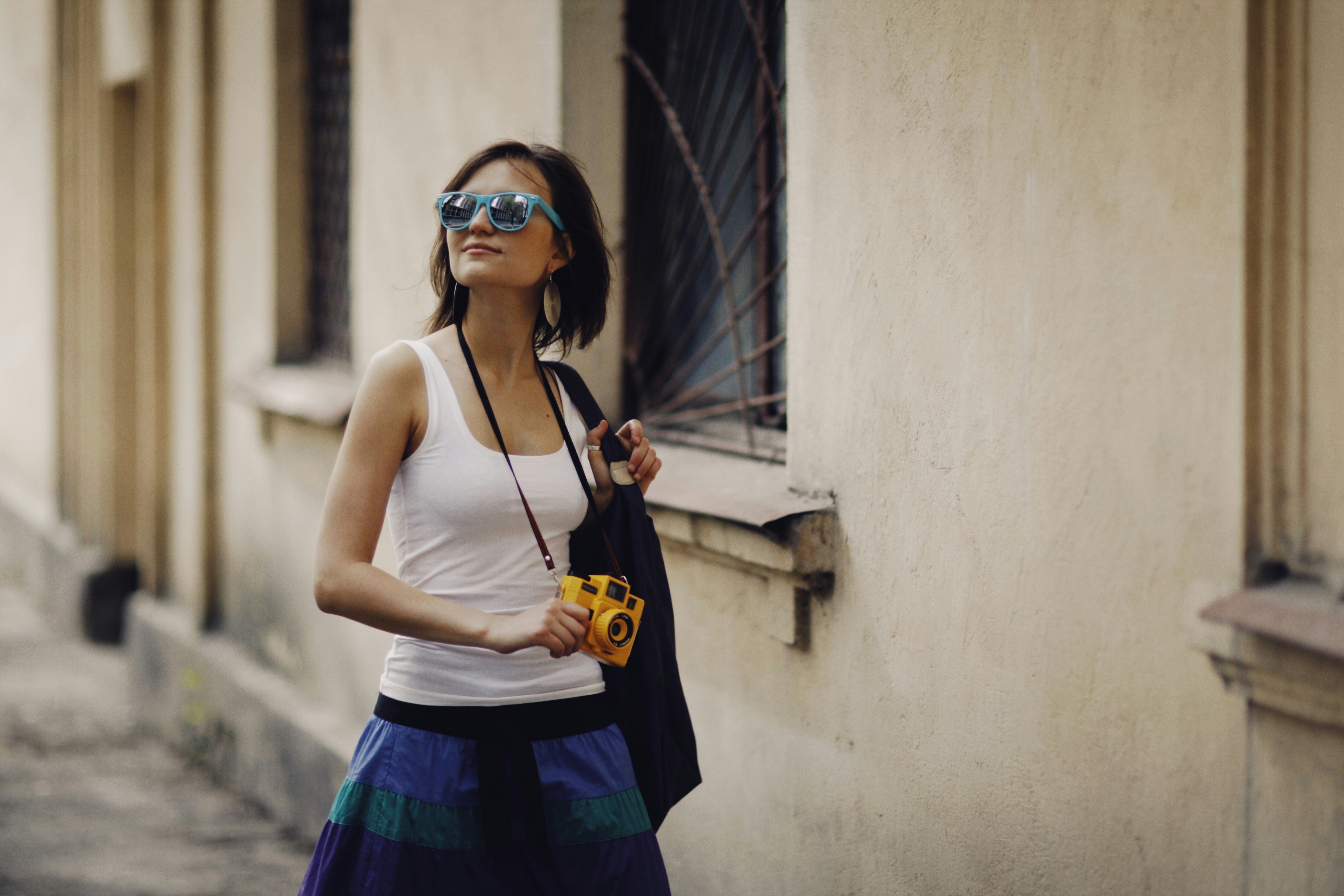 a woman in a white tank top holding a camera
