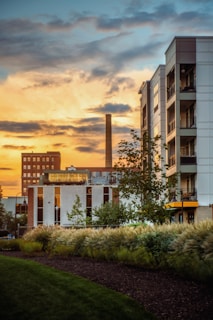 the sun is setting over a building with a clock tower in the background