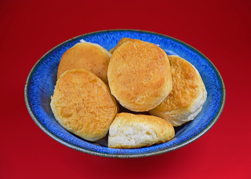 a blue bowl filled with biscuits on top of a red table