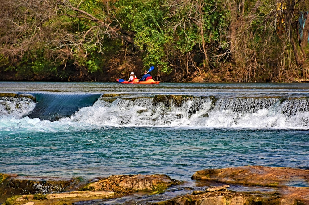 two people are kayaking down a small waterfall