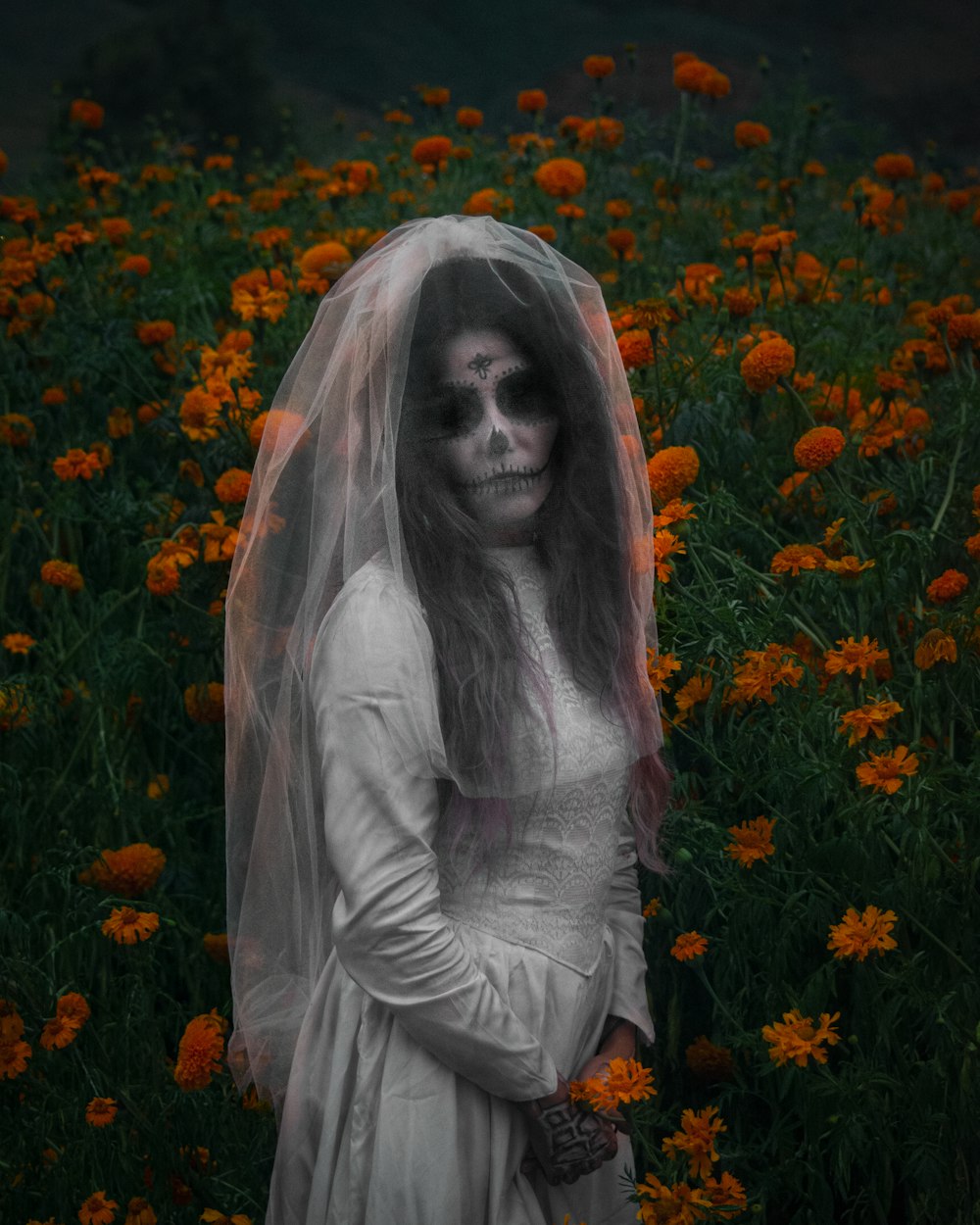 a woman in a white dress and veil standing in a field of flowers