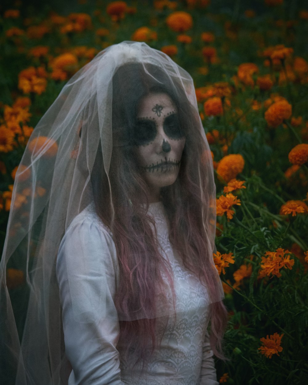 a woman in a white dress with a veil and skull makeup