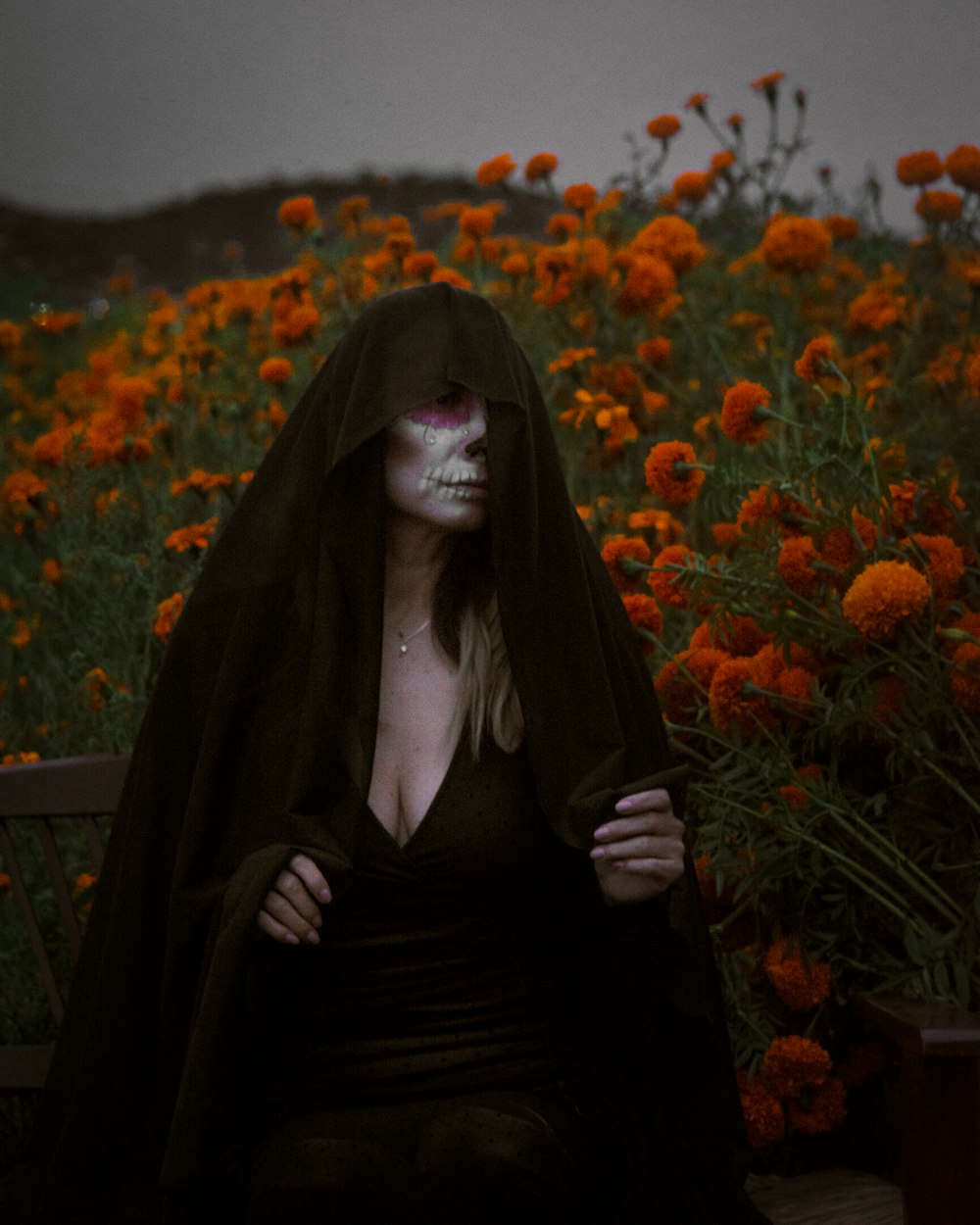 a woman sitting on a bench in a field of flowers