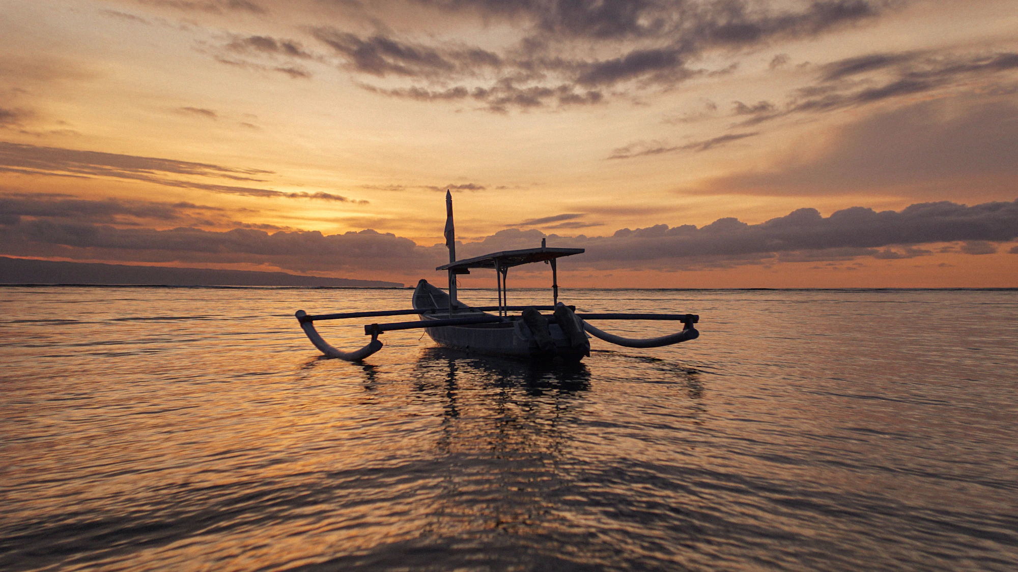 Traditional Balinese outrigger boat on a calm sea at sunrise off Lovina