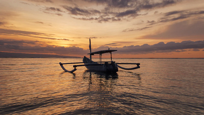 Traditional Balinese outrigger boat on a calm sea at sunrise off Lovina