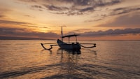 A small boat resting on calm water at golden hour, Bali