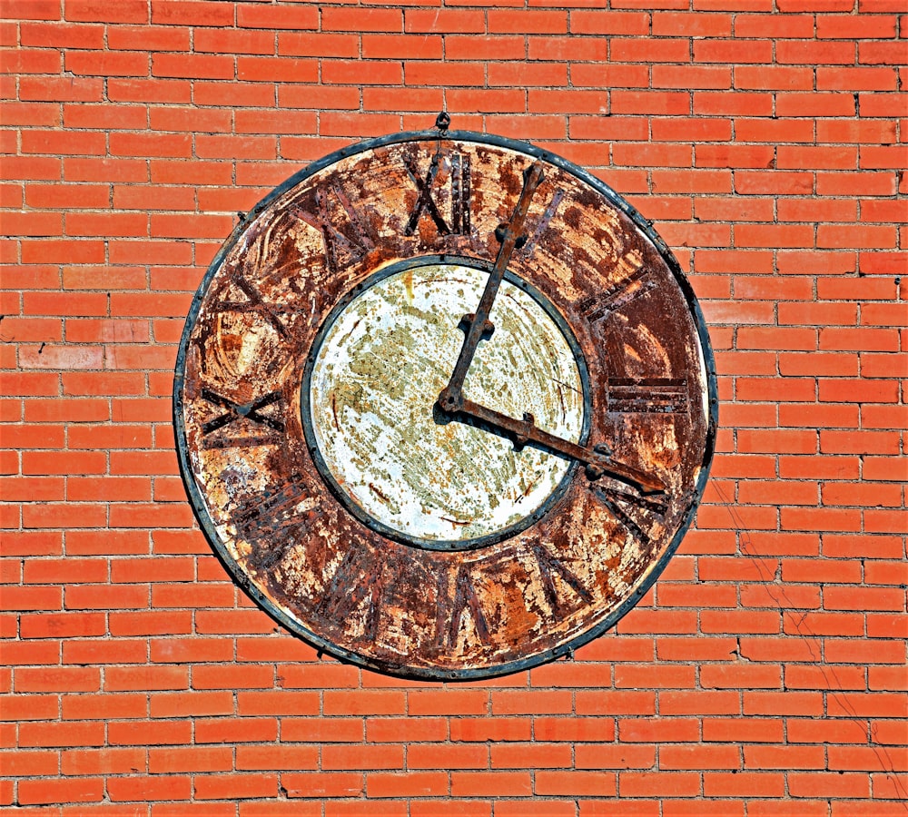 a rusted clock on a brick wall