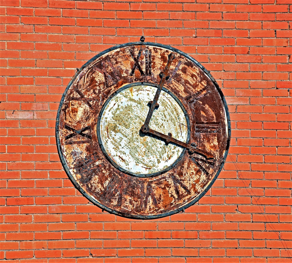 Un reloj oxidado en una pared de ladrillos