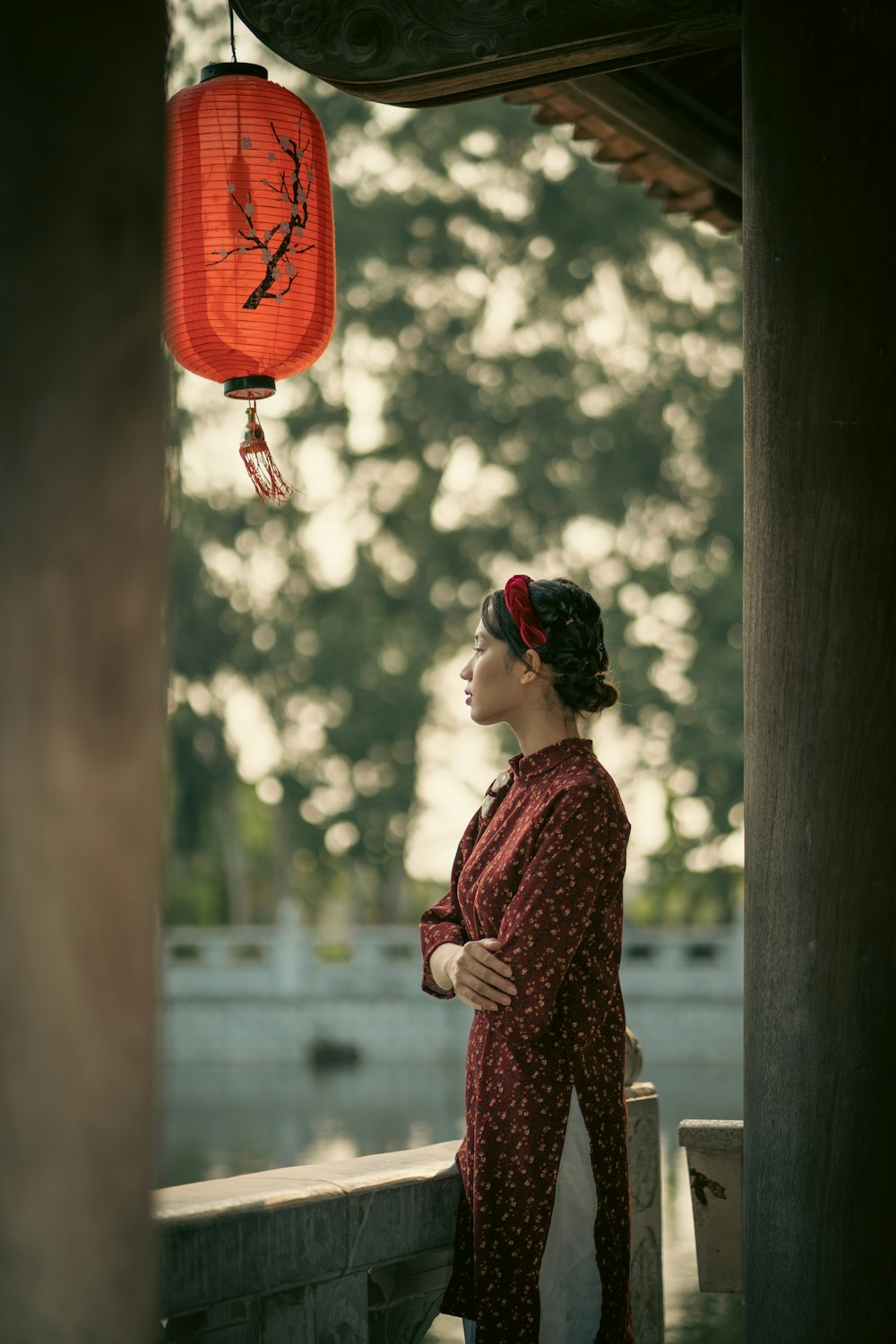 a woman in a red dress standing under a red lantern