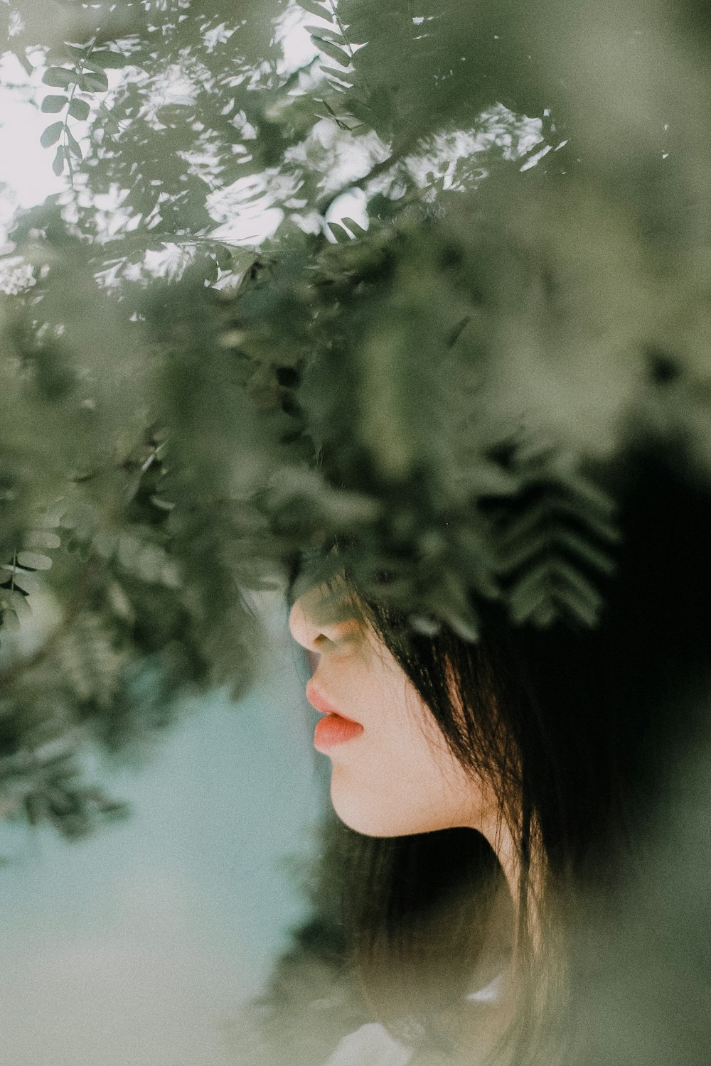 Une femme debout sous un arbre, les yeux fermés