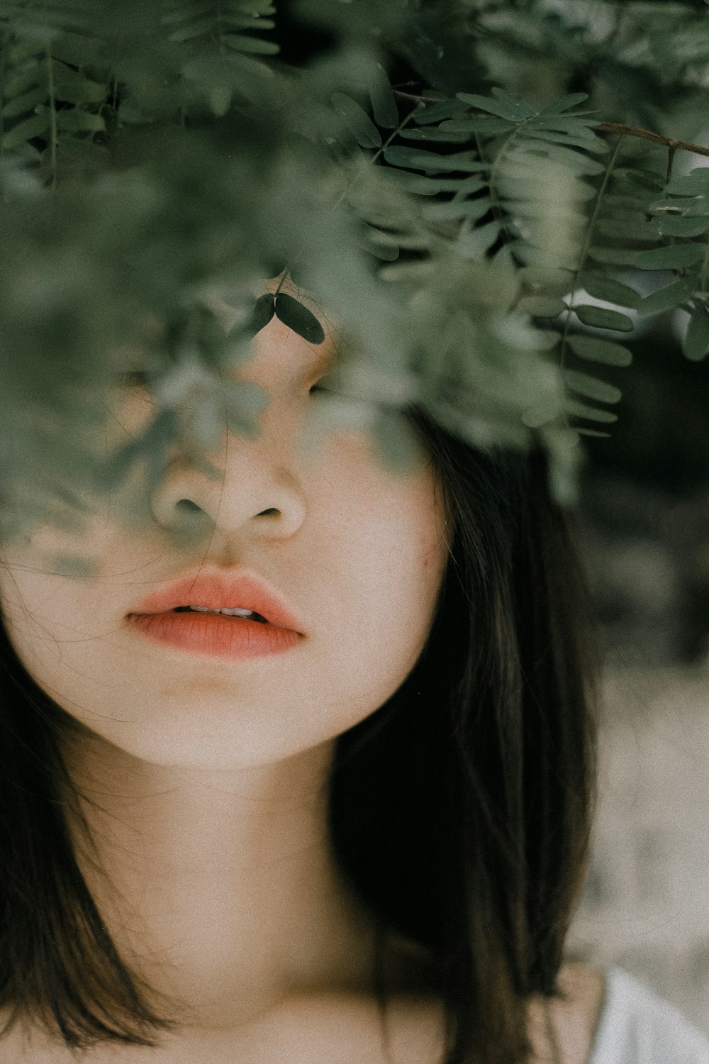 a woman with her eyes closed standing under a tree