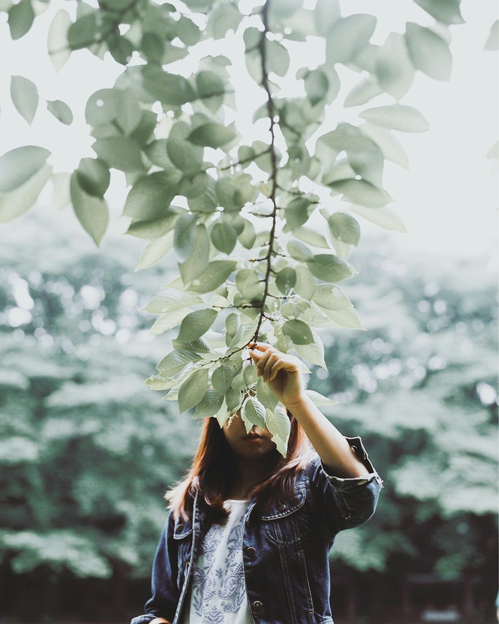 Una donna in piedi sotto un albero con le mani sulla testa