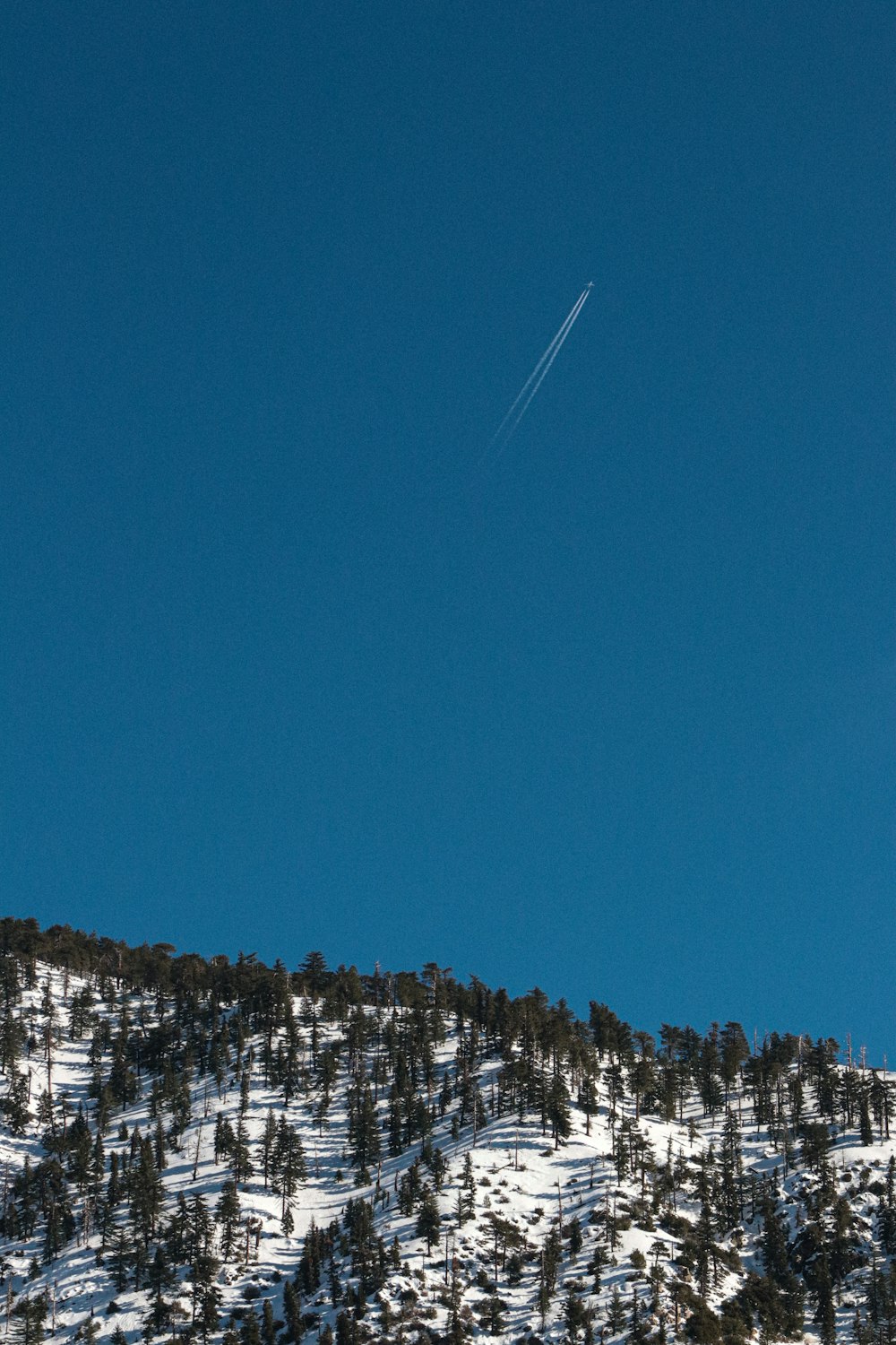 a plane is flying over a snowy mountain