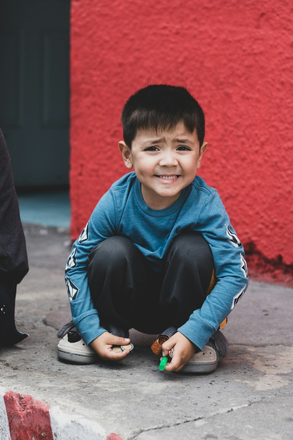 a young boy sitting on the ground smiling
