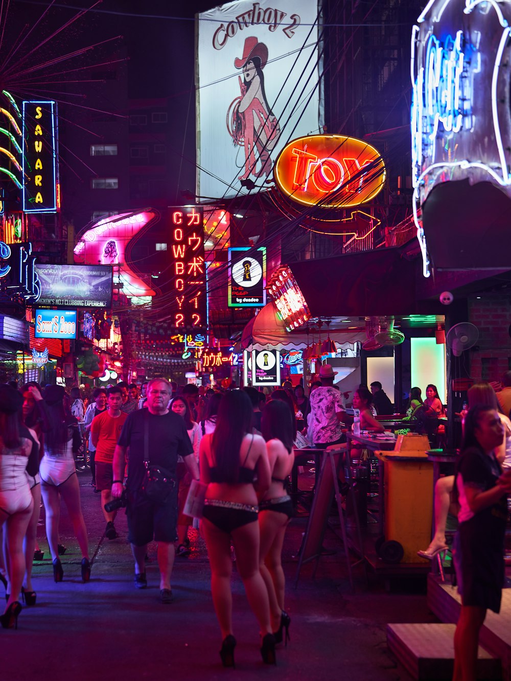 a group of people walking on a city street at night