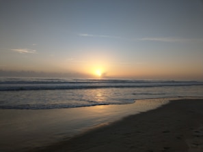 Peaceful sunrise casting soft light over El Sokhna's quiet beach and distant mountains.