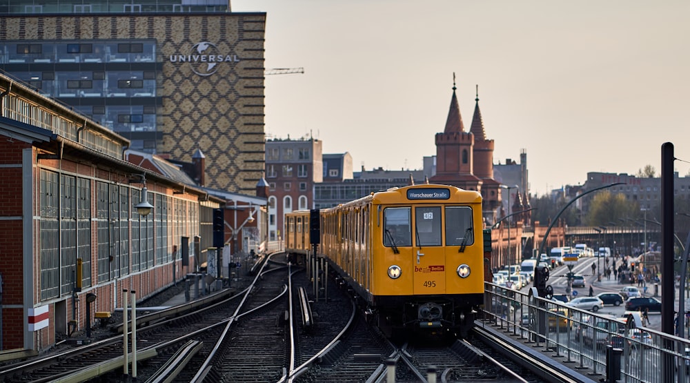 a yellow train traveling down train tracks next to tall buildings
