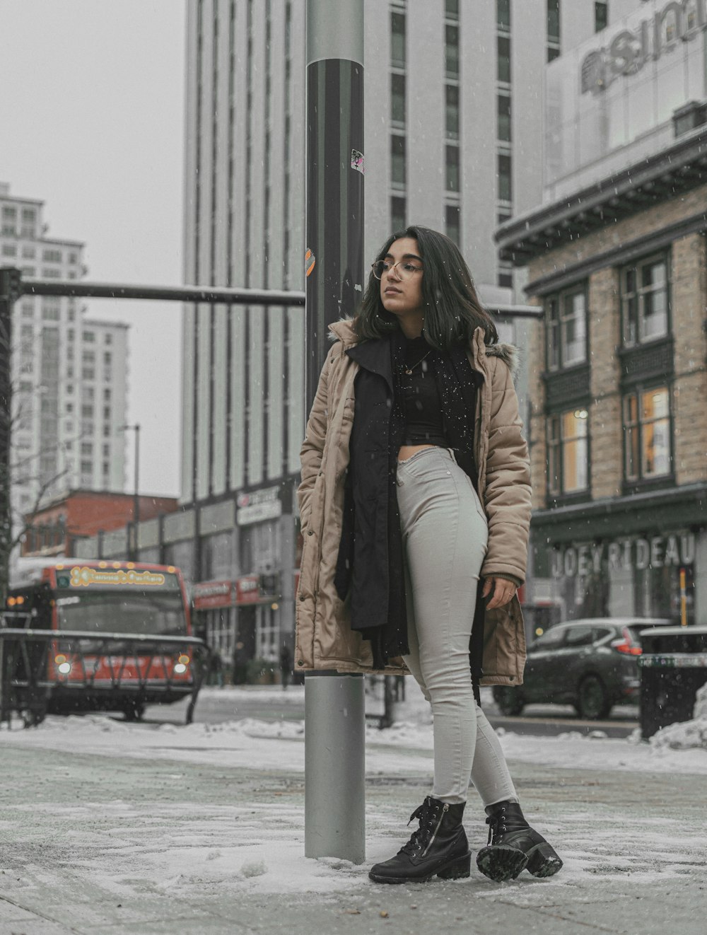 Una mujer parada junto a un poste en la nieve