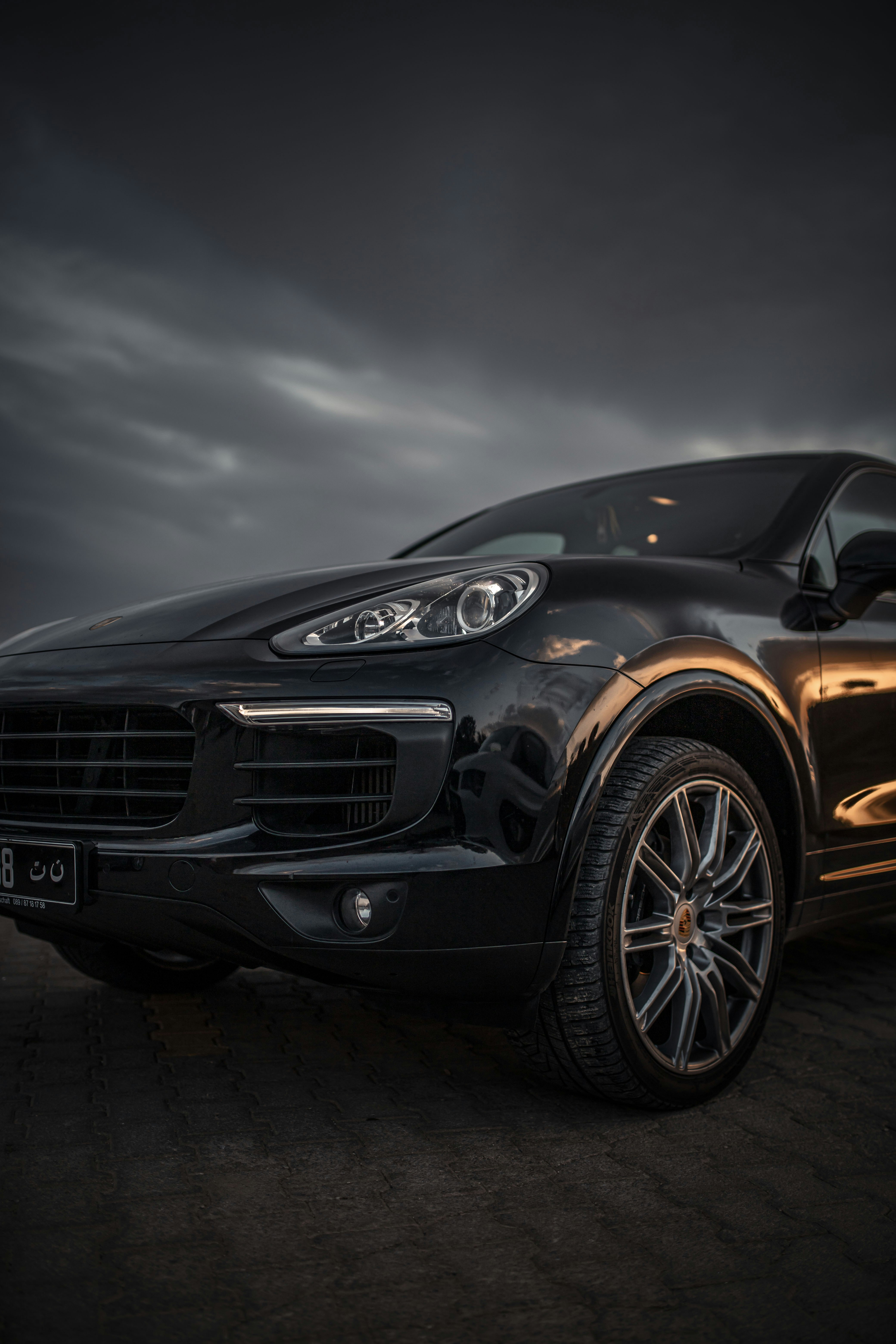 Dark electric SUV crossover on mountain road with overcast dramatic sky and moody atmosphere