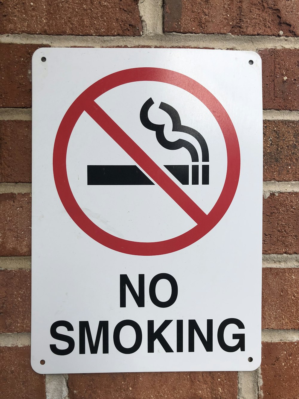 a no smoking sign on a brick wall