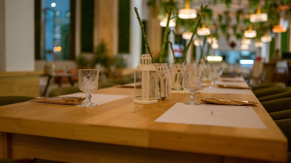 a wooden table topped with glasses and a vase filled with flowers