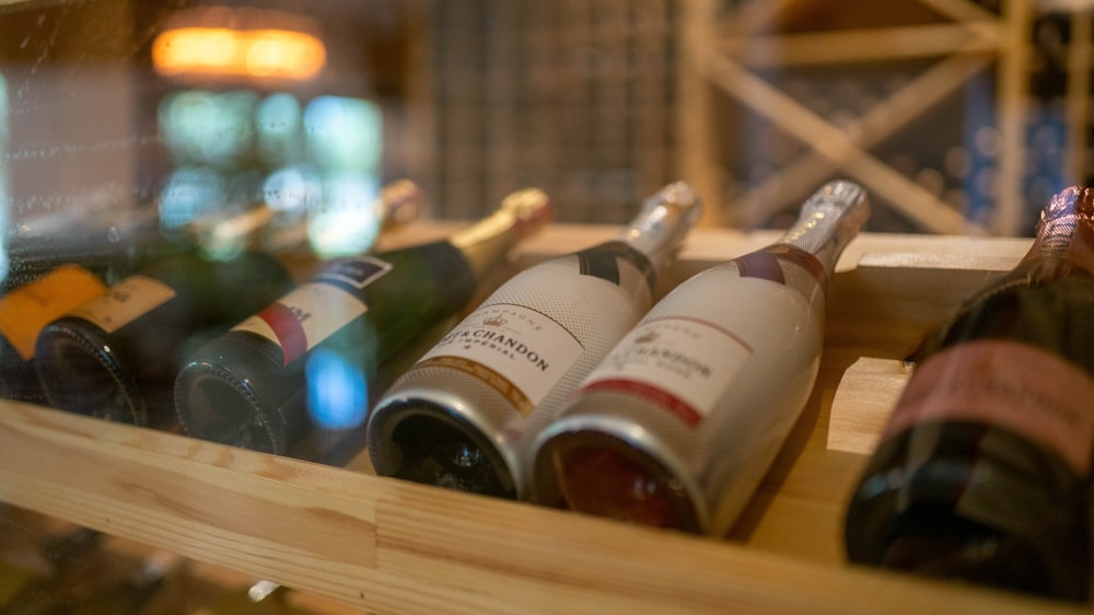several bottles of wine sitting on a wooden shelf