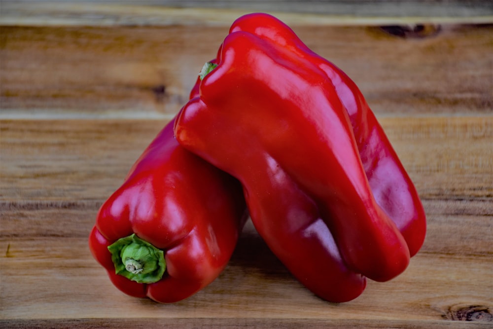 a couple of red peppers sitting on top of a wooden table