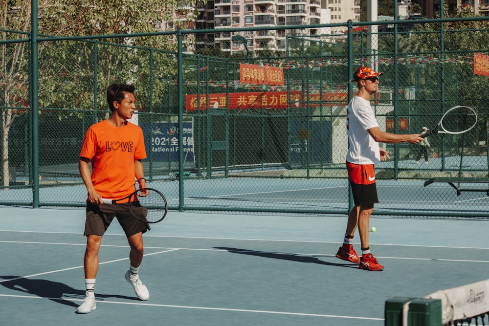 a couple of men standing on a tennis court holding racquets