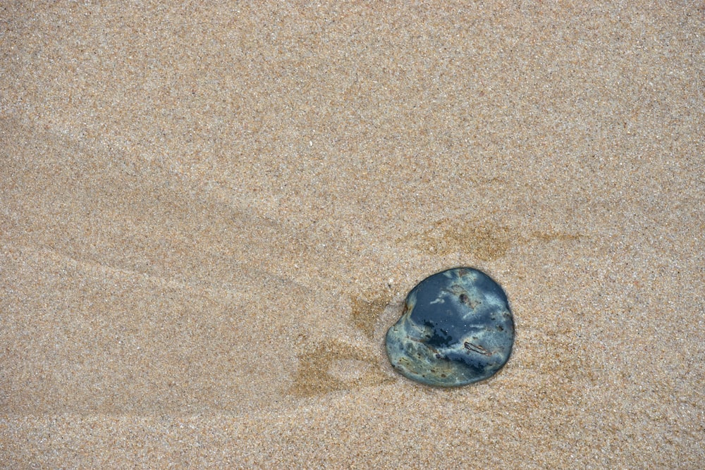 a rock sitting on top of a sandy beach