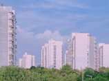 A modern residential apartment complex in Noida with lush green surroundings under a clear blue sky.