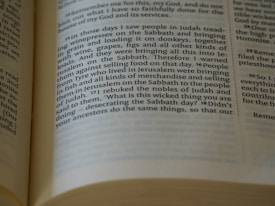 A close-up view of an open book showing a page with printed text in columns. The text focuses on historical and religious themes. The paper appears aged or off-white, suggesting it might be a religious or historical text. The edges of the pages are visible, and the lighting creates slight shadows across the page.