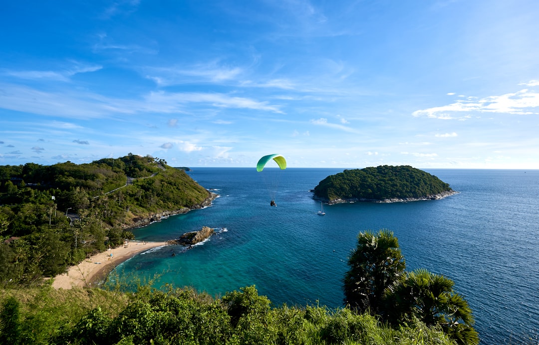 a parasailer glides over a tropical island in the middle of the ocean,