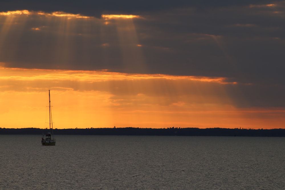 a boat in the water with the sun shining through the clouds