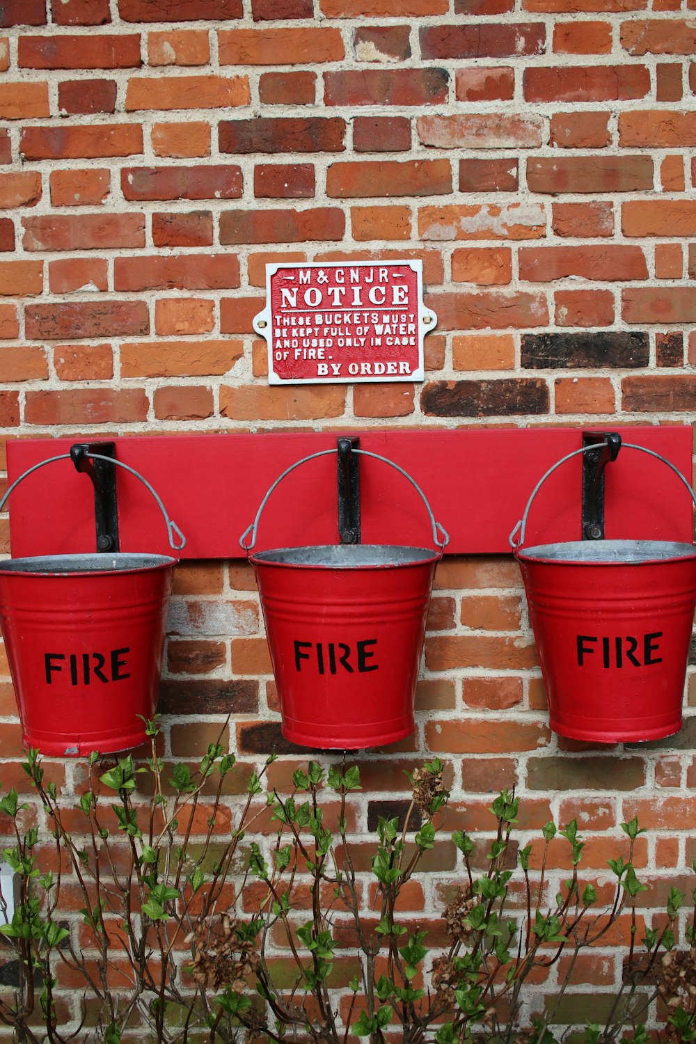 three red buckets are hanging on a brick wall