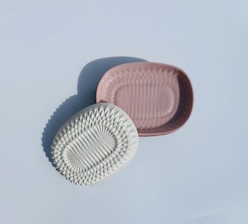 Close-up of a smooth wooden soap dish resting beside a sleek acrylic soap holder on a marble countertop.
