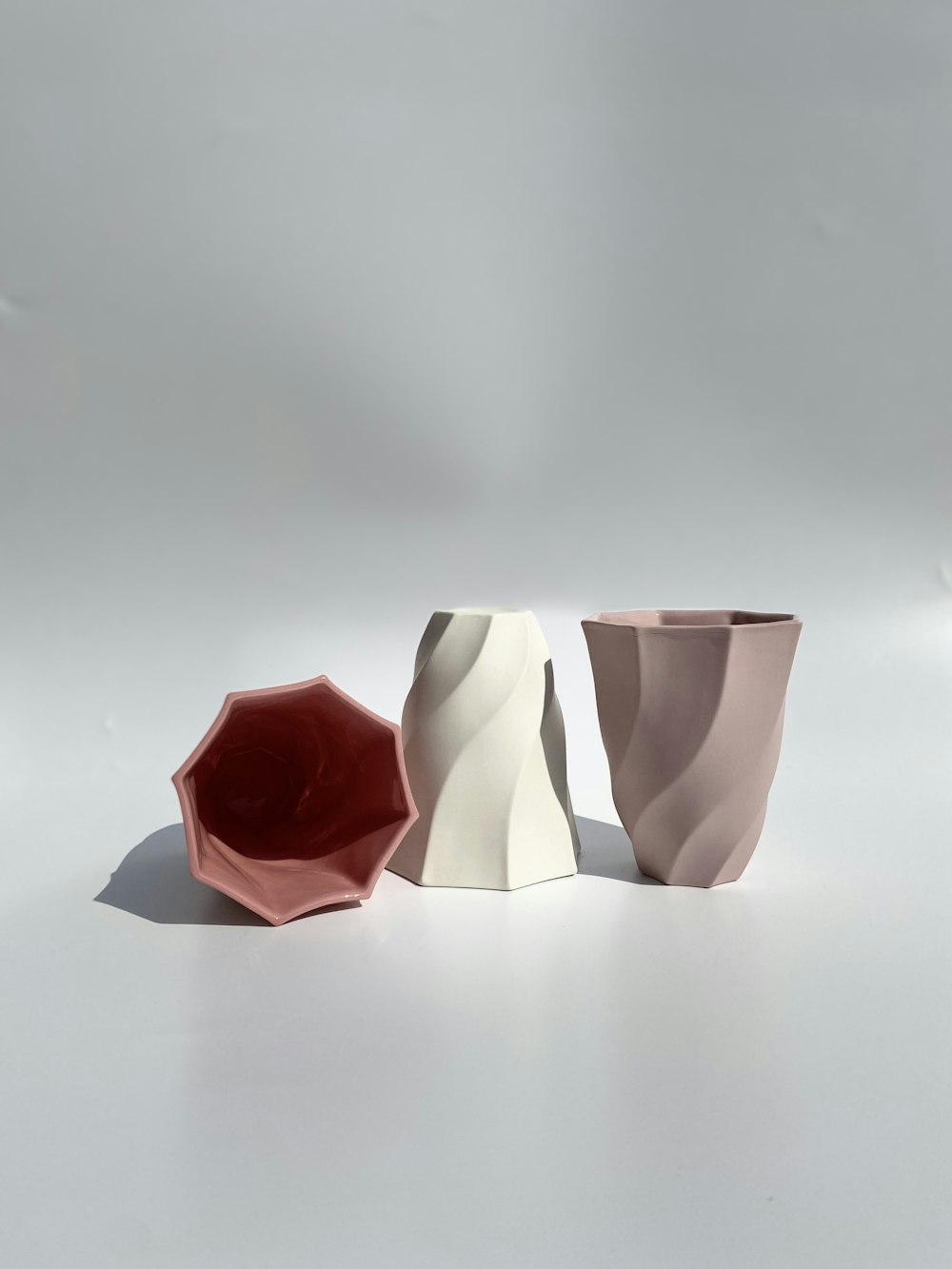 three different shapes of vases on a white surface