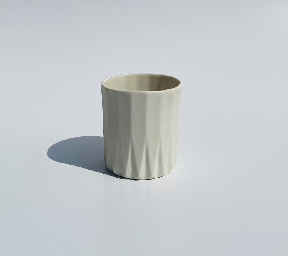a white cup sitting on top of a white table